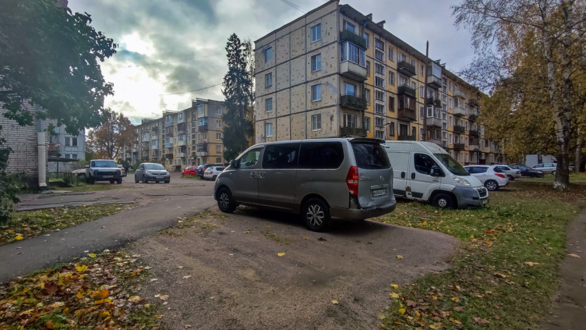 Парковка у жилого квартала с панельными домами и осенними деревьями