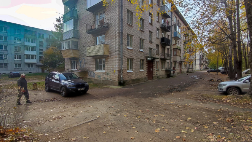 Кирпичный пятиэтажный дом с балконами и припаркованными автомобилями