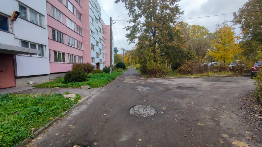 Асфальтовая дорога с выбоинами возле жилых домов