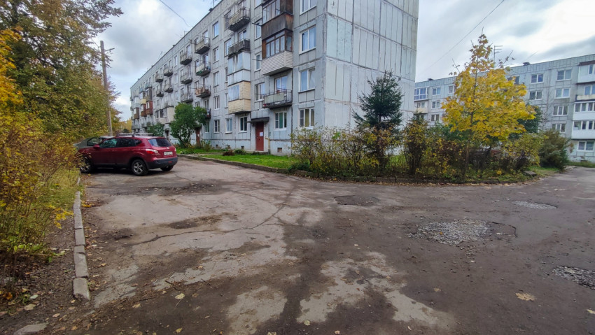 Панельный жилой дом и дворовая дорога с парковкой