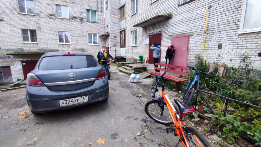 Двор жилого дома с автомобилем и велосипедами у подъезда