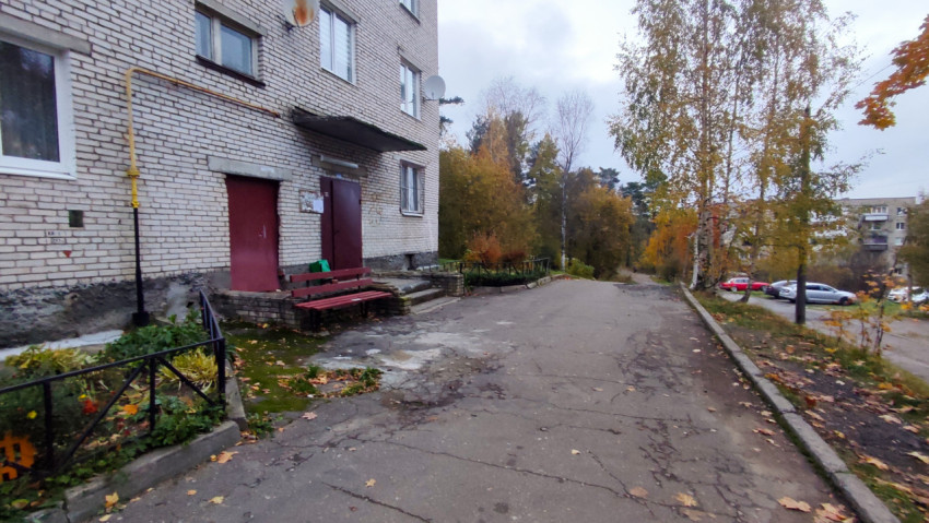 Подъезд кирпичного жилого дома и двор с осенними деревьями