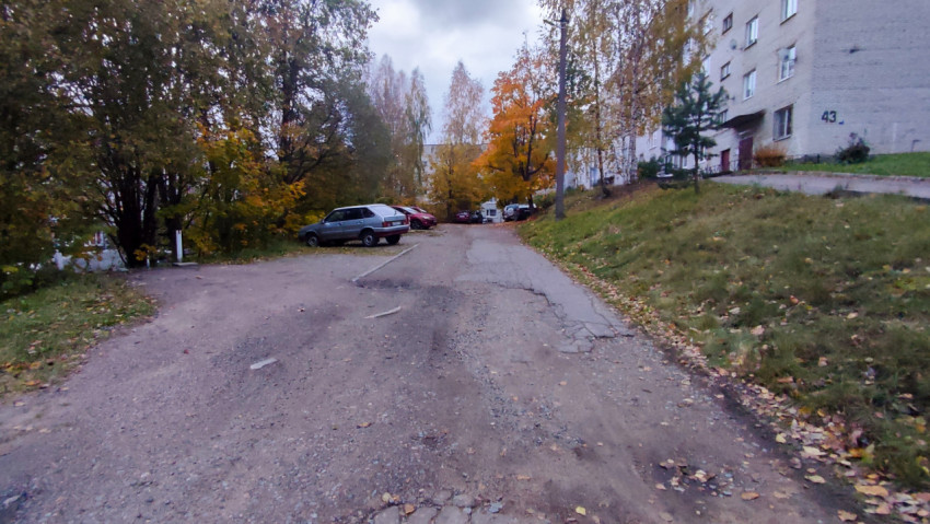 Осенний вид на двор и парковку возле многоэтажного дома