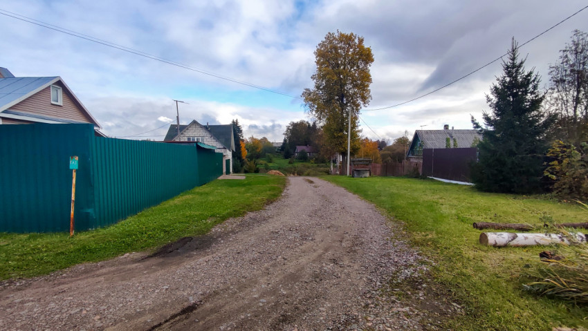 Гравийная дорога между домами и зелёными заборами