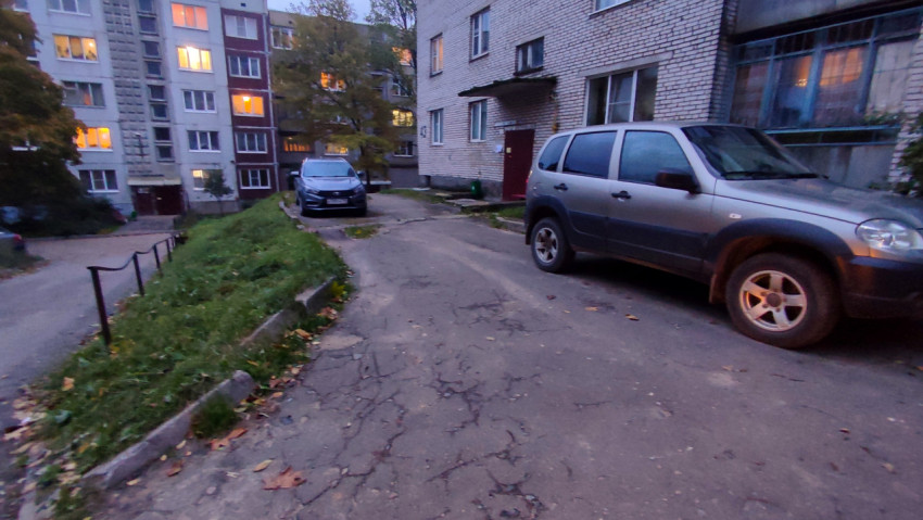 Парковка у подъезда жилого дома с зелёным откосом