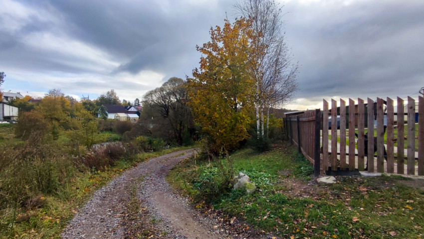 Грунтовая дорога у деревенского забора в осенний день