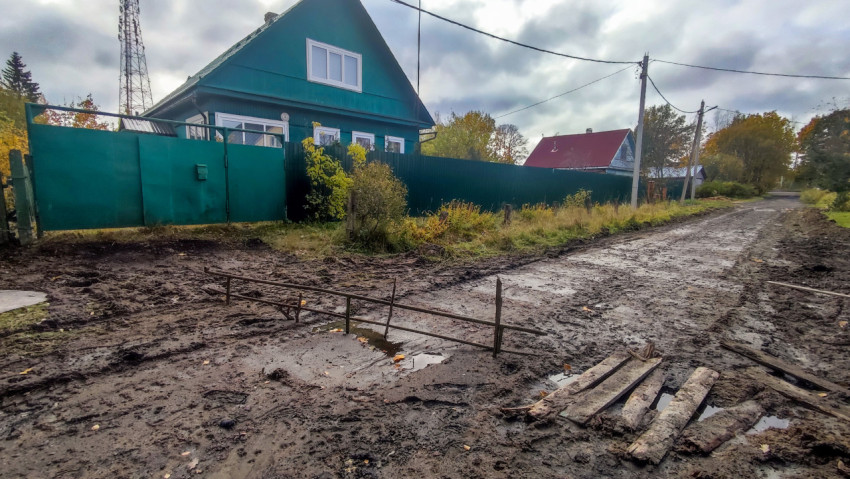 Грунтовая дорога с металлическим ограждением и зелёным домом