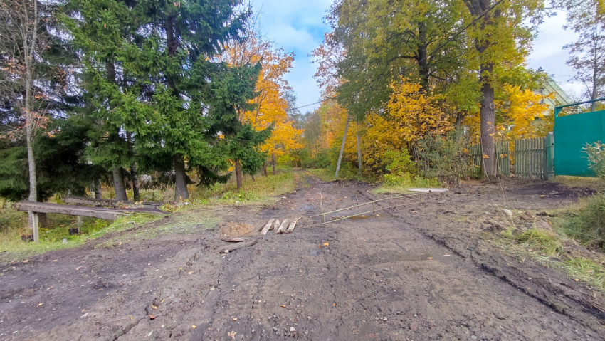 Грунтовая дорога с временным настилом из досок у частного дома