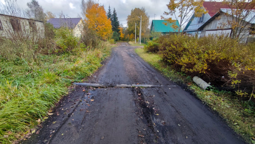 Грунтовая дорога с бетонной трубой водоотвода и частными домами