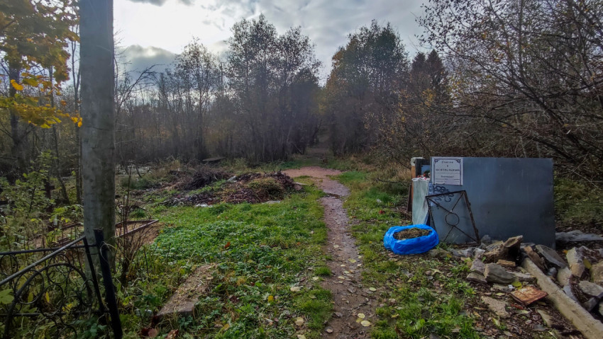 Входная тропа к кладбищу с мусорной площадкой и табличкой