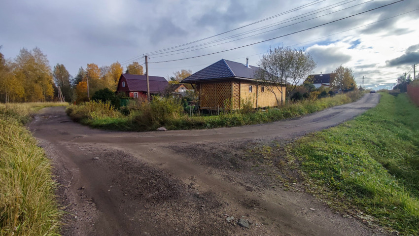 Загородная дорога и частные дома в осеннем пейзаже