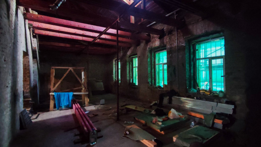 Помещение в кирпичном здании с зелёными окнами и строительными материалами