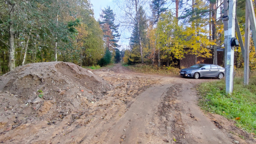 Развилка грунтовых дорог с кучами песка и припаркованным автомобилем