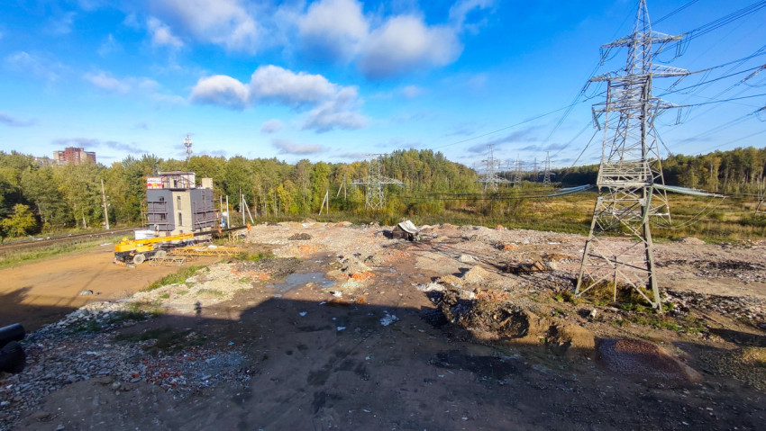 Стройплощадка с линиями электропередачи и лесом на заднем плане
