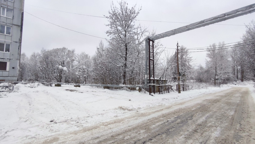 Въезд на заснеженную дворовую территорию с надземным трубопроводом