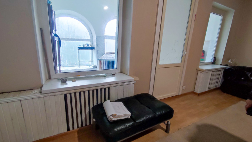 Жилое помещение с большими окнами и документами на кожаном пуфе