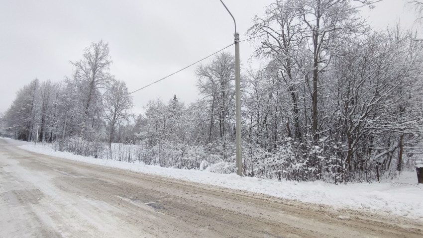 Обочина зимней дороги с опорой линии электропередачи