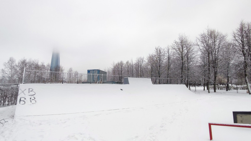 Рампа скейтпарка на фоне зимнего городского пейзажа