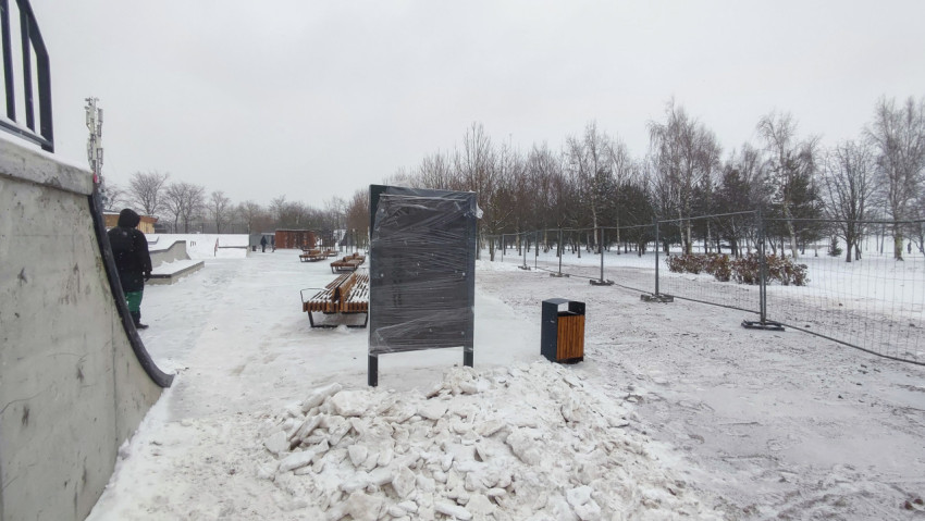 Скамейки и информационный щит в зимней парковой зоне