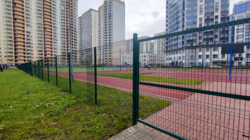 Ограждение спортивного поля и жилые дома в современном квартале