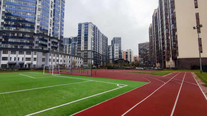 Футбольное поле и беговые дорожки среди жилых домов