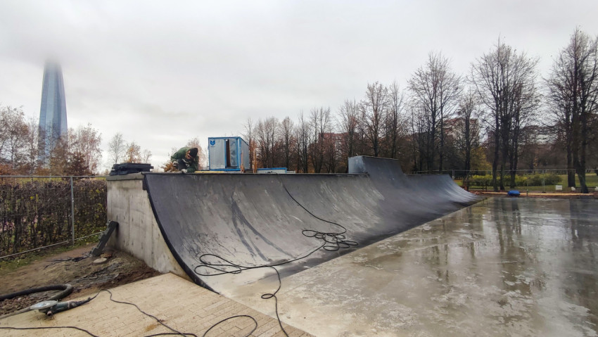 Рабочий выполняет отделку бетонной рампы скейт-парка