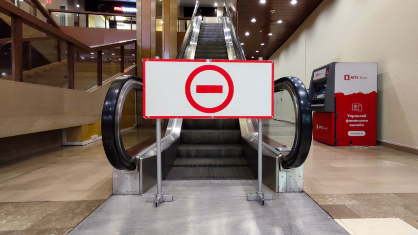 Эскалатор, закрытый для доступа предупреждающей табличкой