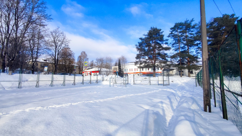 Зимняя площадка у жилых домов и хвойных деревьев