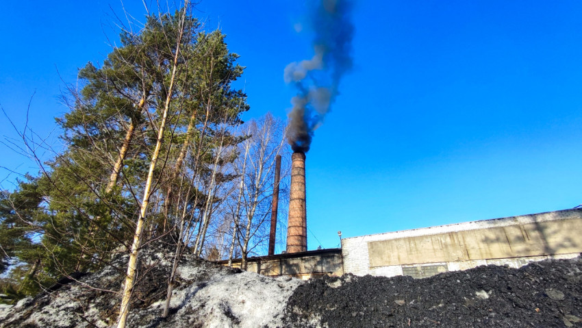 Заводская труба с дымом и остатками угля на переднем плане