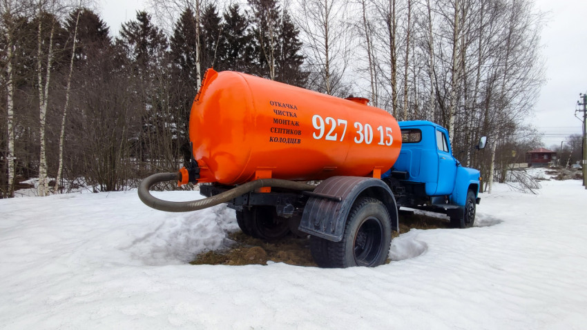 Вакуумный грузовик у леса в зимний день