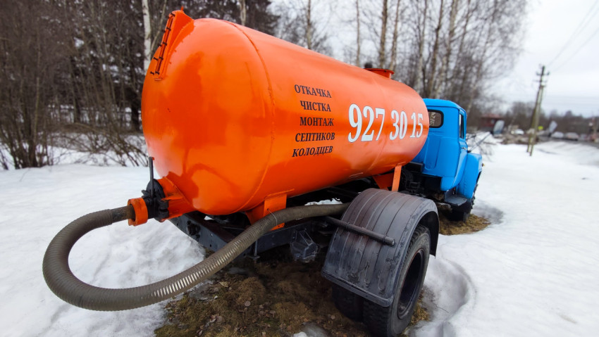 Оранжевая цистерна вакуумного грузовика с синим кузовом на снегу