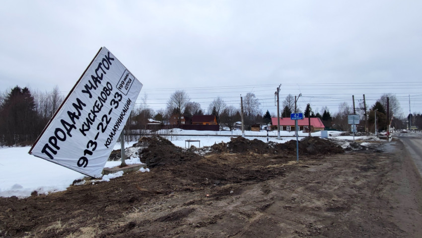 Повреждённый рекламный щит о продаже участка у дороги