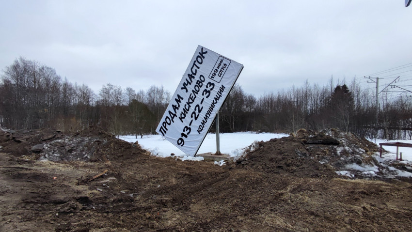 Сломанный рекламный щит о продаже участка в зимнем пейзаже