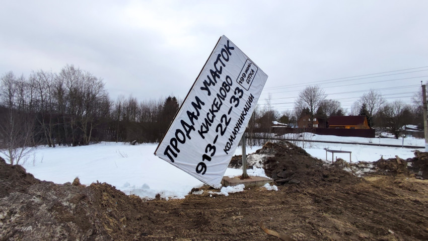Рекламный щит на фоне загородных домов и железнодорожных линий