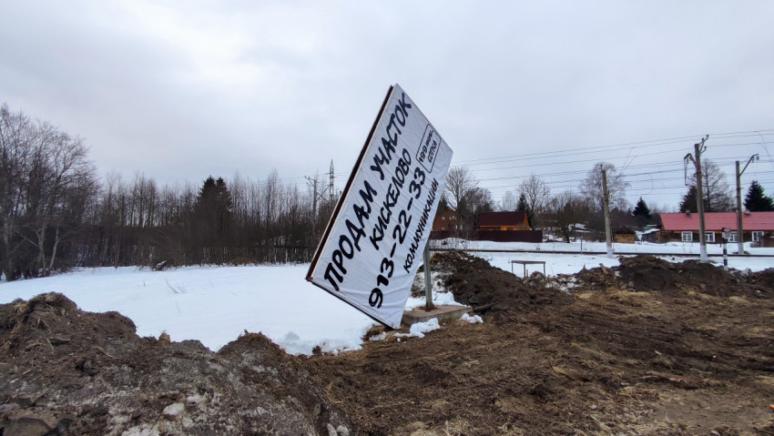 Рекламный баннер о продаже земли у обочины загородной дороги