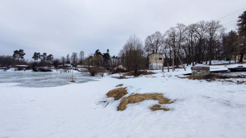 Заброшенные постройки у замерзшего водоёма зимой