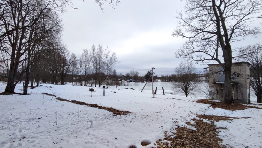 Зимний пейзаж с замёрзшим водоёмом и кирпичным строением