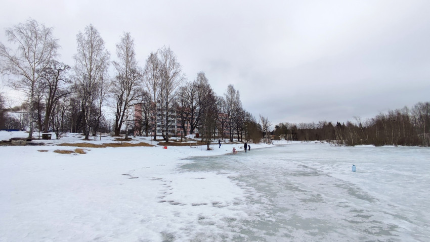 Замерзший пруд с людьми на льду в жилом районе
