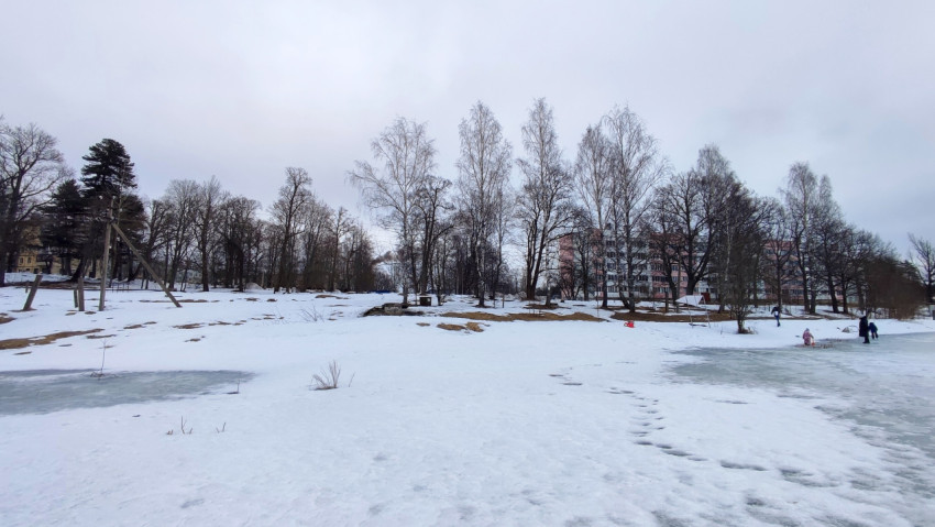 Люди у замерзшего пруда рядом с жилыми домами