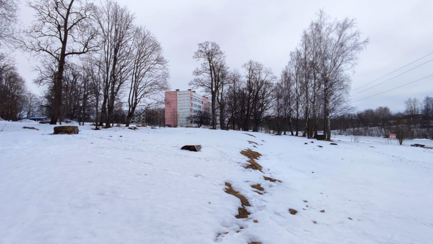 Снежное поле и жилой дом на фоне зимнего неба