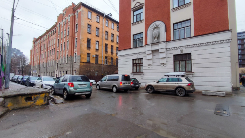 Улица между домами с парковкой и фасадами начала XX века