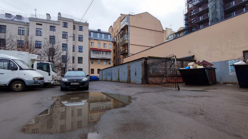 Металлические ворота и контейнеры во дворе старого дома