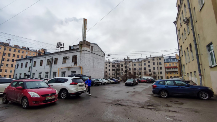Парковка у старого производственного здания с трубой