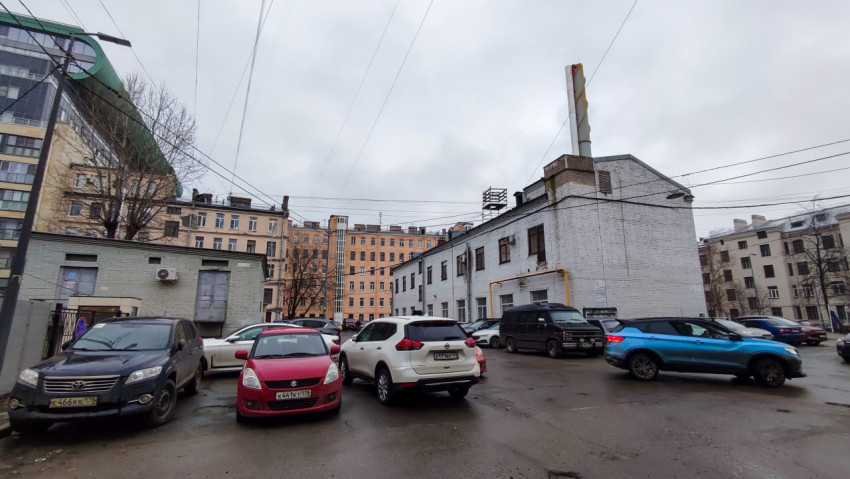 Двор с белым кирпичным зданием и жилыми домами