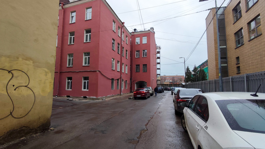 Жилой дом с красным фасадом и парковкой во дворе