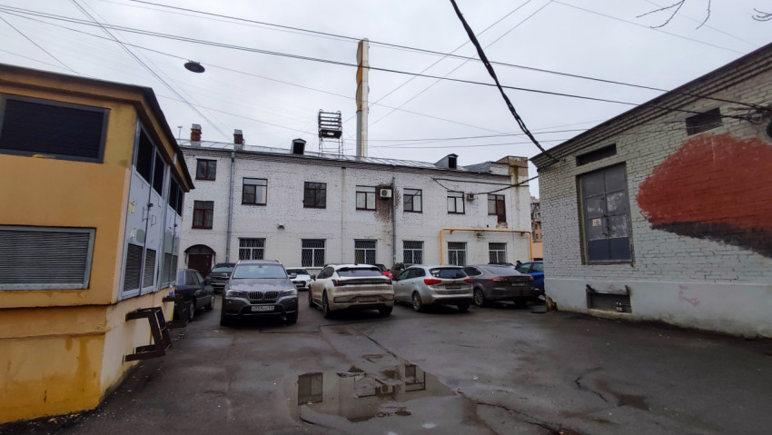 Парковка во дворе старых зданий с кирпичными фасадами