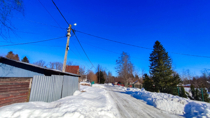 Заснеженная деревенская улица с линиями электропередачи