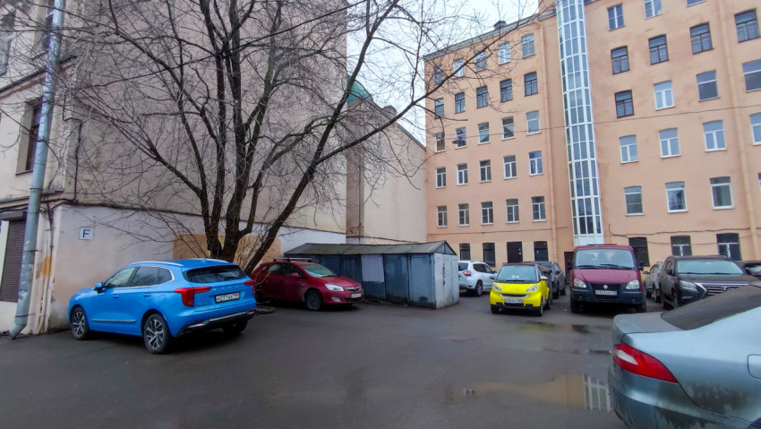 Парковка между жилыми домами с гаражами и деревьями