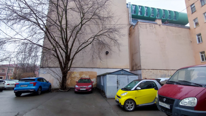 Автомобили у стены жилого дома и металлического гаража