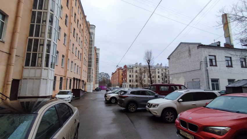 Вид на двор с фасадом жилого дома и припаркованными машинами